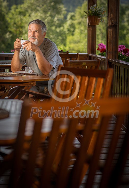 Handsome senior man enjoying his morning coffee on a mountain hotel terrace, while on vacation Handsome senior man enjoying his morning coffee on a mountain hotel terrace, while on vacation