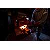 blacksmith manually forging the red hot molten metal on the anvil in traditional smithy workshop. Blacksmith working metal with hammer in the forge