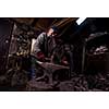 blacksmith manually forging the red hot molten metal on the anvil in traditional smithy workshop. Blacksmith working metal with hammer in the forge