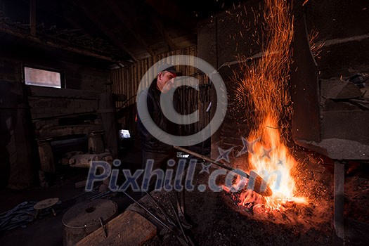 young traditional Blacksmith working with open fire The blacksmith making flames in smithy with spark fireworks forging hot iron in workshop young traditional Blacksmith working with open fire The blacksmith making flames in smithy with spark fireworks forging hot iron in workshop
