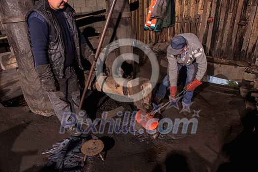 two real brutal traditional blacksmith workers working together with a red hot iron using mechanical hammer at workshop Portrait of a profession two real brutal traditional blacksmith workers working together with a red hot iron using mechanical hammer at workshop Portrait of a profession