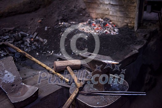 Working tool forge consisting of the anvil, hammer and tongs at blacksmith traditional workshop