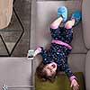 top view of cute little girl using a smartphone and smiling while lying on the sofa at home