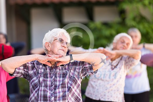 healthy senior woman exercising with friends in front of retirement home