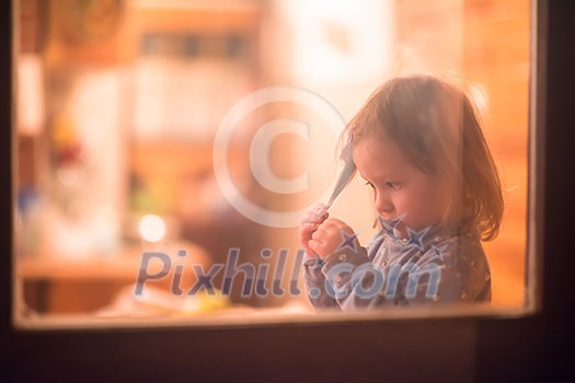 outside view of happy little cute girl playing near the window during winter time at home outside view of happy little cute girl playing near the window during winter time at home