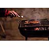 young man cooking meat on barbecue in front of the weekend house on a cold winter day