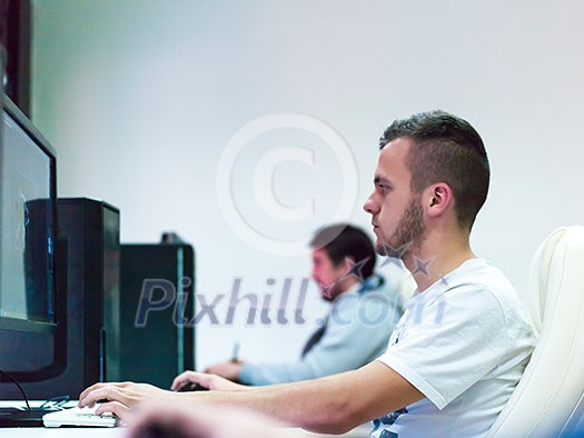 Young Graphic Designer Working at Workplace. Guy Sitting at Table Retouching Photo Using Digital Tablet with Pen and desktop computer Indoors. Freelancing and Distance Job Concept Young Graphic Designer Working at Workplace. Guy Sitting at Table Retouching Photo Using Digital Tablet with Pen and desktop computer Indoors. Freelancing and Distance Job Concept
