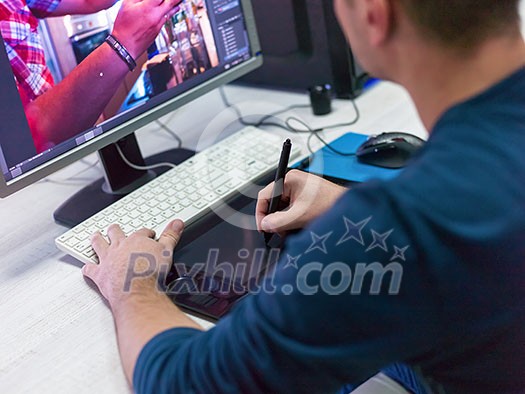 Closeup of Graphic Designer Working at Workplace. Guy Sitting at Table Retouching Photo Using Digital Tablet with Pen and desktop computer Indoors. Freelancing and Distance Job Concept