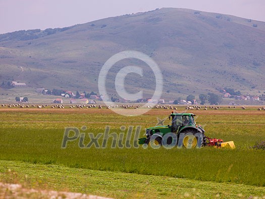 Man driving tractor with large wheels during harvest in the field