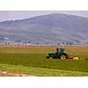 Man driving tractor with large wheels during harvest in the field