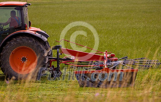 Man driving tractor with large wheels during harvest in the field