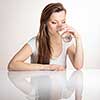 Beautiful, young woman isolated on white background with a reflection underneath her having a drink of clean, fresh water