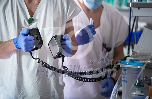 Doctor holding defibrillator electrods, performing defibrillation on a patient, saving a human life Doctor holding defibrillator electrods, performing defibrillation on a patient, saving a human life