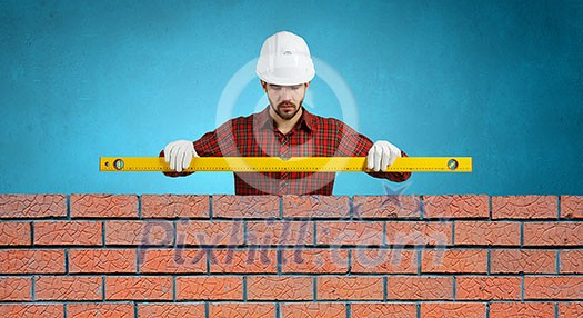 Builder man in checked shirt using measuring level Builder man in checked shirt using measuring level