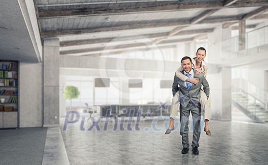 Businesswoman riding on back of her colleague in modern office