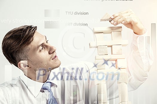 Young businessman making pyramid with empty wooden cubes Young businessman making pyramid with empty wooden cubes