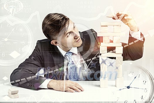 Young businessman making pyramid with empty wooden cubes Young businessman making pyramid with empty wooden cubes