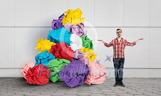 Young man in modern interior and paper balls as symbol of creativity