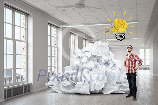 Young man in modern interior and paper balls as symbol of creativity Young man in modern interior and paper balls as symbol of creativity