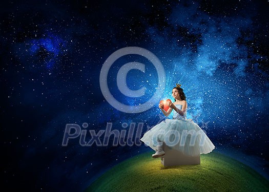 Little girl princess in blue dress with diadem on head and red heart in hands