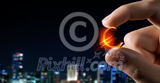 Tiny euro currency sign holden between fingers Tiny euro currency sign holden between fingers
