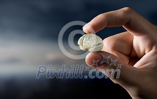 Close view of male hand taking with fingers human brain Close view of male hand taking with fingers human brain