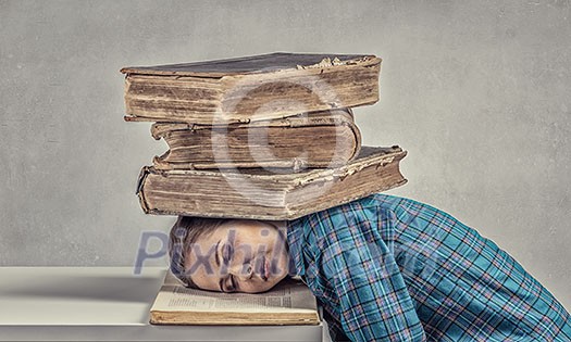 Student girl pressed with pile of books to table