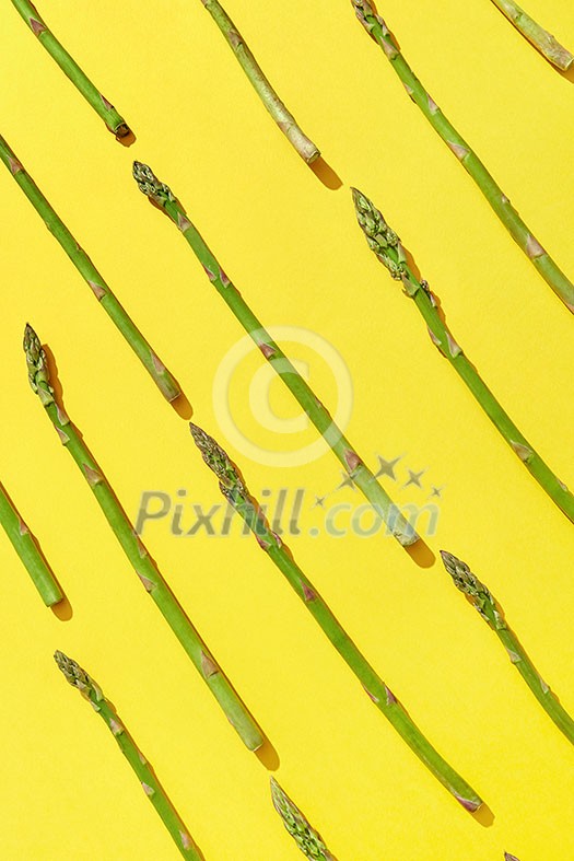 Diagonal pattern of freshly picked natural green asparagus on an yellow background with shadows. Top view. Vegetarian nutrition concept. Diagonal pattern of freshly picked natural green asparagus on an yellow background with shadows. Top view. Vegetarian nutrition concept.