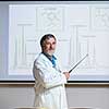 Senior chemistry professor giving a lecture in front of classroom full of students (shallow DOF; color toned image)