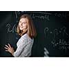 Pretty, young female student/teacher in front of a blackboard during math class