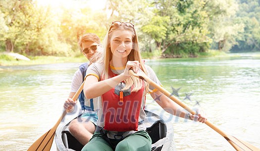 Couple adventurous explorer friends are canoeing in a wild river surrounded by the beautiful nature Couple adventurous explorer friends are canoeing in a wild river surrounded by the beautiful nature
