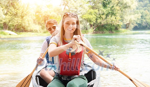 Couple adventurous explorer friends are canoeing in a wild river surrounded by the  beautiful nature