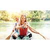 Couple adventurous explorer friends are canoeing in a wild river surrounded by the  beautiful nature