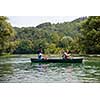 Couple adventurous explorer friends are canoeing in a wild river surrounded by the  beautiful nature