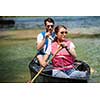 Couple friends are canoeing in a wild river surrounded by the  beautiful nature