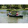 Couple friends are canoeing in a wild river surrounded by the  beautiful nature