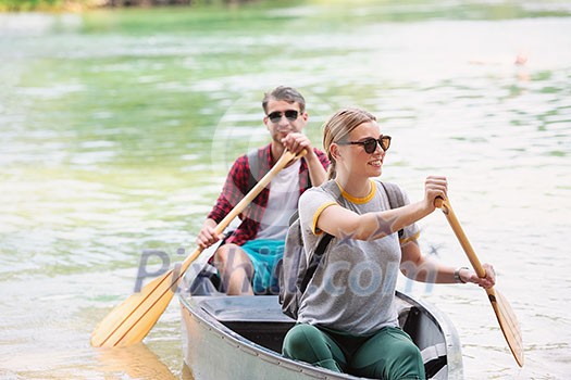 Couple adventurous explorer friends are canoeing in a wild river surrounded by the  beautiful nature