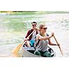 Couple adventurous explorer friends are canoeing in a wild river surrounded by the  beautiful nature