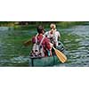 Couple adventurous explorer friends are canoeing in a wild river surrounded by the  beautiful nature