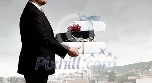 Young businessman in office with boxes of gifts in hands Young businessman in office with boxes of gifts in hands
