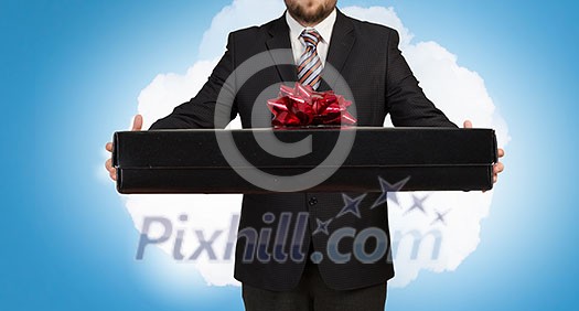 Young businessman in office with boxes of gifts in hands