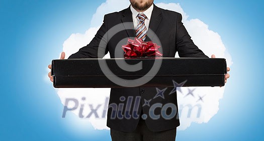 Young businessman in office with boxes of gifts in hands Young businessman in office with boxes of gifts in hands