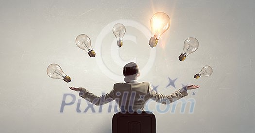 Young businesswoman sitting in chair and light bulbs above