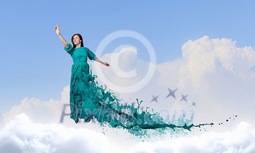 Elegant woman in green long dress walking on clouds