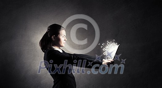 Young businesswoman holding tablet on dark background