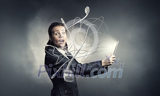 Young emotional businesswoman holding tablet on dark background