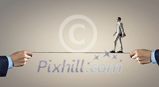 Businessman walking on rope presenting risk and danger concept
