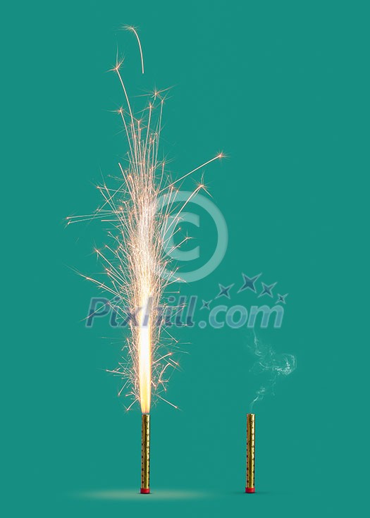 Burning firework with bright sparkes and smoke from burnt candle on a turquoise background, copy space. Concept of festive event.