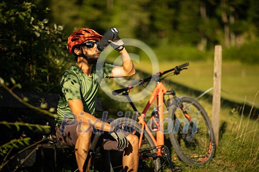 Young man biking on a mountain bike enjoying healthy active lifestyle outdoors in summer (shallow DOF