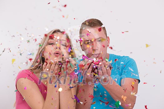 young romantic couple in love celebrating and blowing confetti decorations young romantic couple in love celebrating and blowing confetti decorations